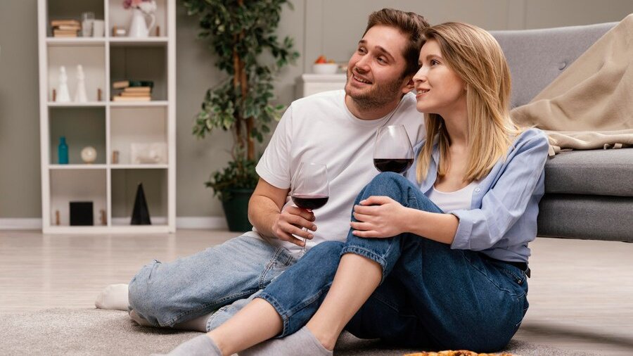 Genç çift pizza ve şarap kadehleriyle yerde oturup film izliyor. Genç çift pizza ve şarap kadehleriyle yerde oturup film izliyor.