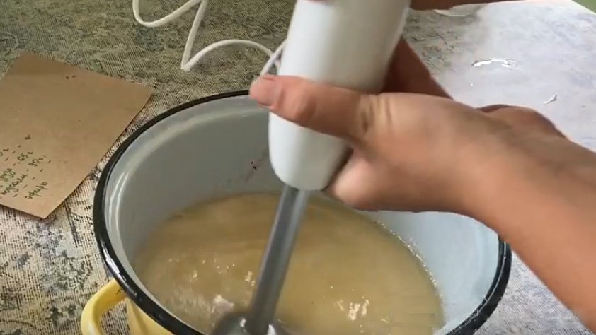 Blenderli bir adam bir karışımı tavada karıştırır.